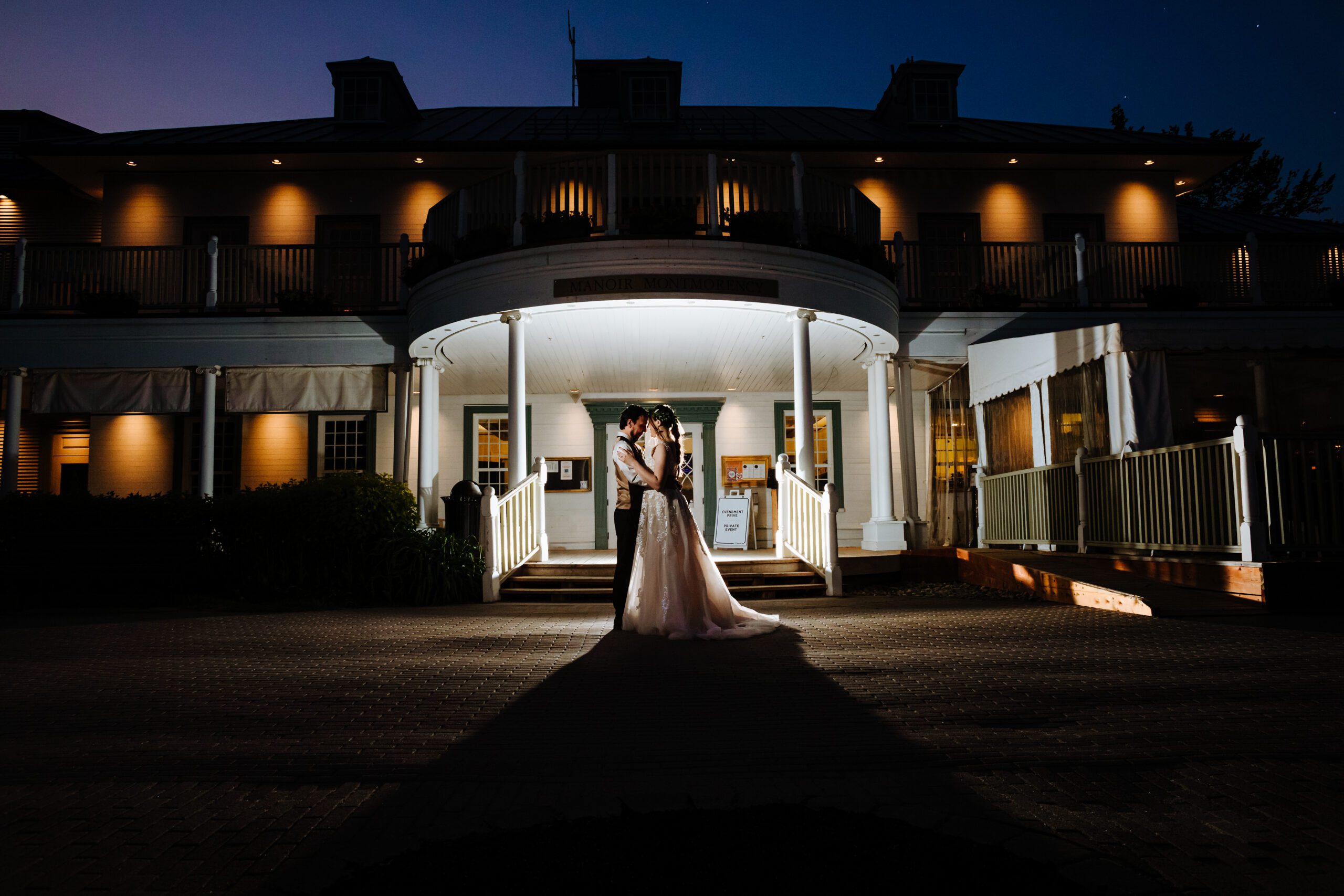 bride and groom in front of the Manoir Montmorency at night